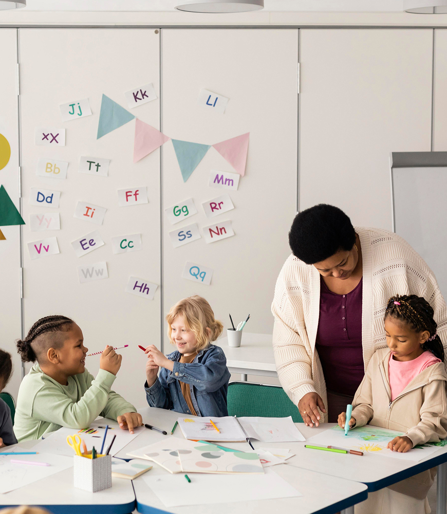Children drawing together with a teacher in a classroom